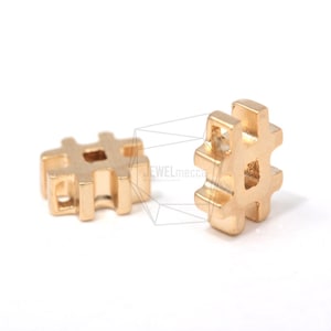 Könnte beinhalten: Zwei goldfarbene Metall-Anhänger in Form des Hashtag-Symbols. Die Anhänger sind klein und haben ein detailliertes Design.