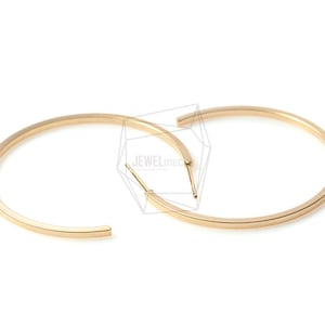 Puede incluir: Un par de pendientes de aro de oro. Los aros son gruesos y tienen un diseño simple y moderno.