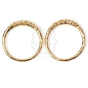 May include: Two gold rings with a textured, beaded design. The rings are simple and delicate.
