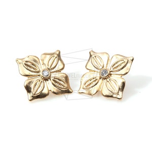 May include: A pair of gold flower-shaped earrings with a clear rhinestone in the center of each flower.