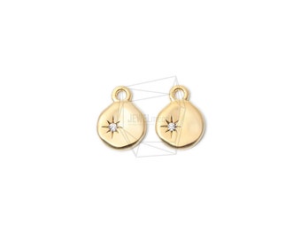 May include: Two gold-colored pendants with a matte finish. Each pendant has a rounded shape with a small loop at the top and a starburst design with a small, clear gem in the center. The pendants are displayed against a white background.