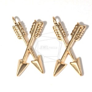 May include: Two gold-toned arrow charms with a criss-cross design. The arrows have a detailed feathered design and pointed tips.