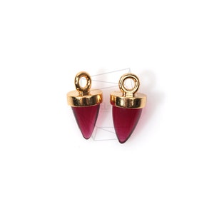 May include: Two gold-toned pendant charms with a pointed, teardrop-shaped red glass stone.