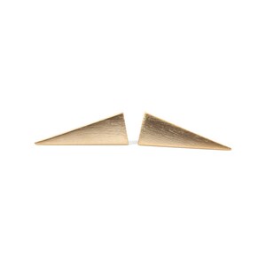 May include: A pair of gold triangle earrings. The earrings are made of a brushed metal and have a simple, geometric design.