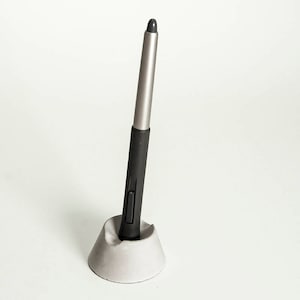 May include: A black and silver stylus pen in a gray concrete holder.