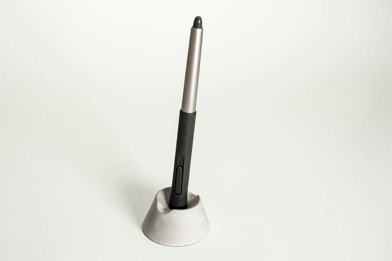 May include: A black and silver stylus pen in a gray concrete holder.