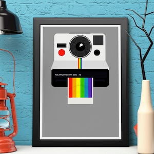 May include: A vintage Polaroid camera with a rainbow film strip emerging from the front. The camera is white with black accents and the text "POLAROID FLOYD DARK SIDE 73" is printed on the front.