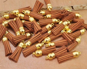 May include: A pile of brown suede tassels with gold metal caps. The tassels are approximately 2 inches long.
