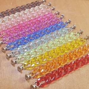 May include: A set of 11 clear plastic chain links in various colors, including brown, clear, pink, purple, blue, light blue, green, yellow, orange, and red. Each chain link has a silver metal clasp.