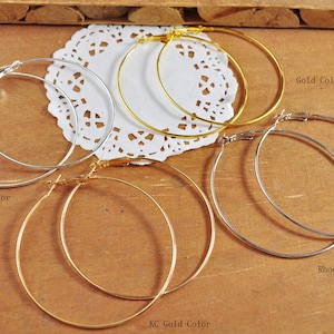 May include: Four pairs of hoop earrings in different finishes: silver, gold, rhodium, and a second gold finish labelled "KC Gold Color".