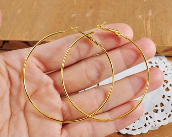 May include: A pair of gold hoop earrings. The earrings are large and circular, and they are made of a thin metal.