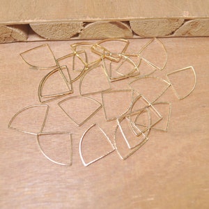 May include: A collection of gold-toned metal half-circle shapes, arranged in a random pattern on a wooden surface.