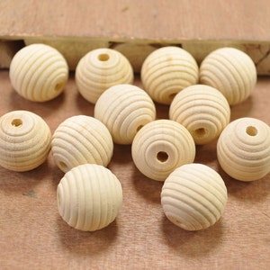 May include: A collection of 12 natural wood beads with a grooved texture. The beads are round and have a hole in the center for stringing.