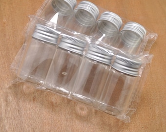 May include: A set of eight clear glass bottles with silver lids. The bottles are packaged in a clear plastic bag.