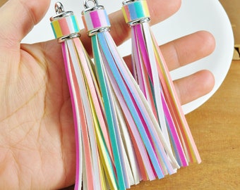 May include: Three colourful striped leather tassels with silver metal tops. The tassels are made of multiple thin strips of leather in pink, yellow, blue, and white.