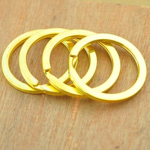 May include: Four gold-colored metal key rings stacked on top of each other.