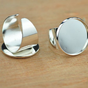 Op de afbeelding: Twee verstelbare zilveren ringen met een ronde bezel-setting. De ene ring heeft een platte bezel en de andere heeft een verhoogde bezel.