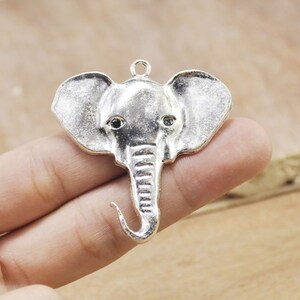 May include: Silver elephant charm pendant with black eyes. The charm is detailed with a textured trunk and ears.