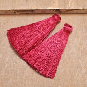 May include: Two burgundy silk tassels with a pointed end. The tassels are made of soft, silky threads and are perfect for adding a touch of elegance to any project.