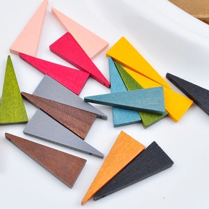 Puede incluir: Surtido de formas triangulares de madera en varios colores, incluyendo rosa, rojo, verde, azul, amarillo, marrón, gris y negro. Los triángulos son de diferentes tamaños y están dispuestos sobre una superficie blanca.