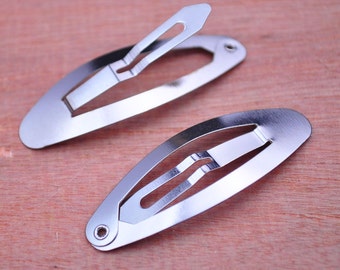 May include: Two silver metal hair clips, each with a simple oval shape and a smooth, shiny finish.