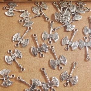 May include: A collection of silver-toned axe-shaped charms with a loop at the top for attaching to jewelry or other crafts.