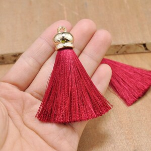May include: Two red silk tassels with gold metal tops. The tassels are approximately 2 inches long.