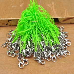 May include: A pile of lime green string with silver lobster clasps. The string is about 15 cm long and is perfect for making keychains, phone charms, or other crafts.