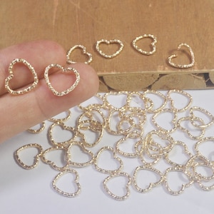 May include: A large quantity of gold-colored heart-shaped metal charms. The charms are small and delicate, with a textured surface.
