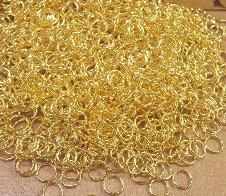 Puede incluir: Un mont&oacute;n grande de anillos de salto de metal de color dorado. Los anillos son todos del mismo tama&ntilde;o y est&aacute;n dispuestos en un patr&oacute;n aleatorio.