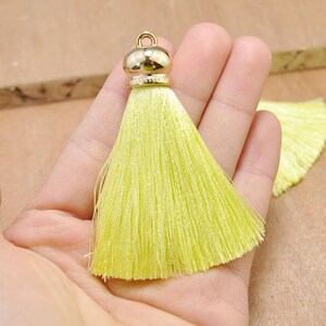 May include: A bright yellow tassel with a gold metal top. The tassel is made of soft, silky threads and is approximately 2 inches long.