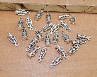 May include: A collection of silver-toned metal charms shaped like oil lamps. Each charm has a loop at the top for attaching to jewelry or other crafts.