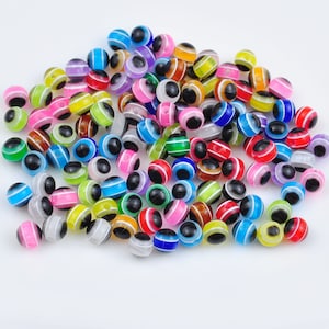 May include: A large pile of colorful plastic beads with black eyes. The beads are striped with various colors, including red, blue, green, yellow, and pink.