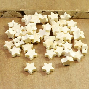 May include: A pile of unfinished wooden star-shaped beads. The beads are light brown and have a hole drilled through the centre.