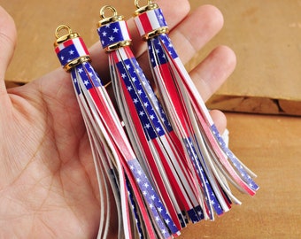 May include: Three white, red and blue tassel keychains with gold metal tops. Each tassel features the American flag design.