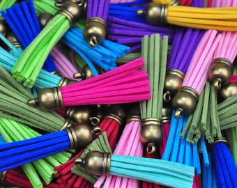 Puede incluir: Surtido de borlas de colores con tapas de metal dorado. Las borlas están hechas de un material suave y peludo y están disponibles en una variedad de colores, incluyendo verde, azul, rosa, rojo y morado.