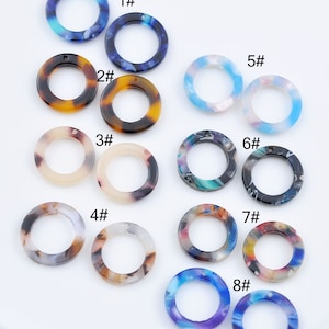 Könnte beinhalten: Acht Paare bunte, runde, dekorative Ringe aus Kunststoff mit einem Loch in der Mitte. Jedes Paar ist von 1 bis 8 nummeriert.