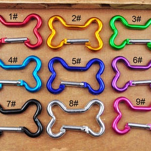 Puede incluir: Nueve cierres de metal en forma de hueso de colores con puertas de resorte. Los cierres están numerados del 1 al 9.