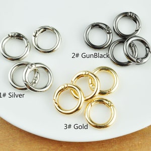 May include: Three sets of silver, gun black, and gold metal key rings. Each set contains two key rings. The key rings are round and have a spring-loaded clasp.