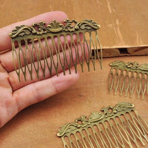 May include: Three antique gold-toned hair combs with ornate floral designs. Each comb has a decorative top and a row of teeth.