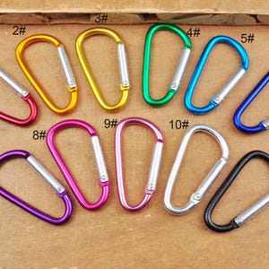 May include: Eleven colorful metal carabiners with numbered tags. The carabiners are in various colors, including red, yellow, green, blue, purple, and silver.