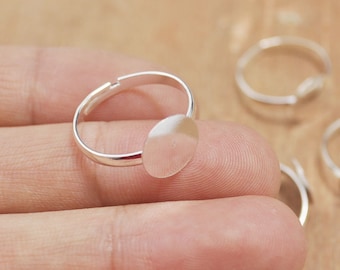 May include: Silver adjustable ring with a round bezel for a cameo or other embellishment.