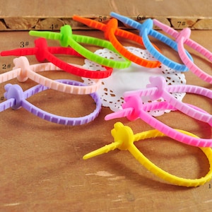 Puede incluir: Diez bridas de cable reutilizables de colores, en varios colores, incluyendo morado, rosa, amarillo, azul, verde, naranja y rojo. Las bridas están numeradas del 1 al 10.