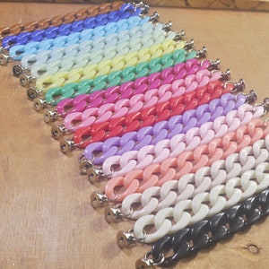 May include: A collection of 18 colorful plastic chain links, each with a silver clasp. The chains are arranged in a rainbow pattern, starting with brown and ending with black.