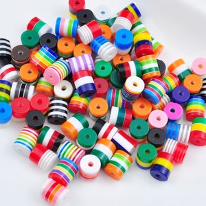 Puede incluir: Una colección de cuentas de madera coloridas, rayadas y con patrones. Las cuentas son de varios tamaños y formas, y algunas tienen un acabado brillante.