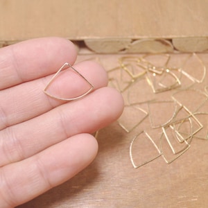 May include: A pile of gold-colored metal triangle shapes, some are stacked on top of each other. The triangle shapes are about 1 inch in size.