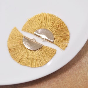 May include: Two gold-toned half-circle tassel earrings with a fringe of yellow tassels.