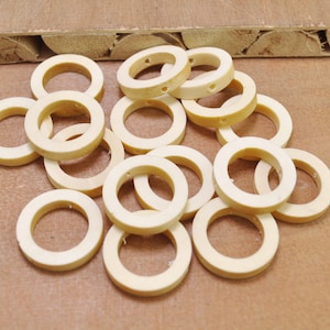 Puede incluir: Un montón de 15 anillos de madera natural con un agujero en el centro. Los anillos son de color marrón claro y tienen un acabado liso.