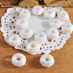 May include: A collection of white iridescent glass beads with a hole in the center. The beads are arranged on a white doily.