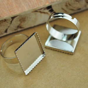 May include: Two silver ring blanks with square bezels. The bezels have a scalloped edge. The rings are for making custom jewelry.